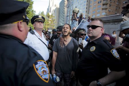 A protester is surrounded by New York Police Department officers before being detained during a rally for Eric Garner who was killed one year ago by police in New York in this July 17, 2015, file photo. REUTERS/Eduardo Munoz/Files