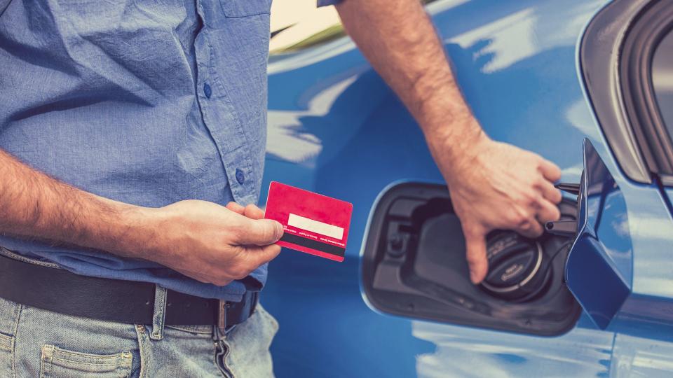 Man with credit card opening fuel tank of his new car.