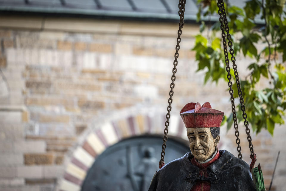 The sculpture of Cardinal Franz Hengsbach hangs on the chains of a crane during dismantling in front of Essen Cathedral in Essen, Germany, Monday Sept. 25, 2023. The statue of late German Cardinal Franz Hengsbach was removed from outside a cathedral in western Germany after allegations of sexual abuse against him surfaced. (Christoph Reichwein/dpa via AP)