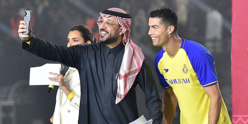 topshot al nassrs new portuguese forward cristiano ronaldo r, wearing a cross earing, poses for a selfie with the presenters during his unveiling at the mrsool park stadium in the saudi capital riyadh on january 3, 2023 photo by afp photo by afp via getty images