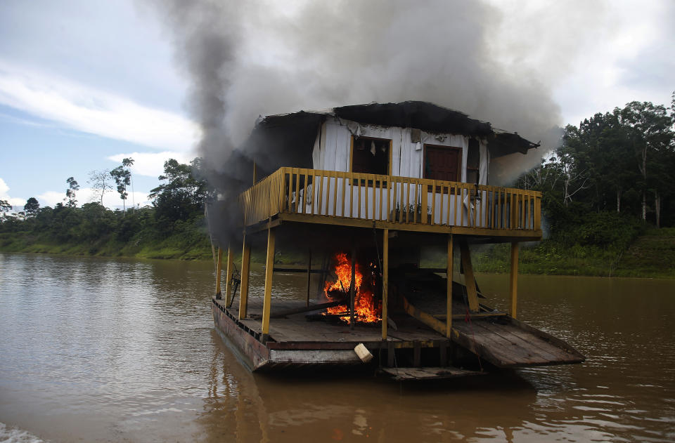 One of the more than 60 dredging barges that were set on fire by officers of the Brazilian Institute of the Environment and Renewable Natural Resources, IBAMA, drifts on the river during an operation to try to contain illegal gold mining on the Madeira river, a tributary of the Amazon river in Borba, Amazonas state, Brazil, Sunday, Nov. 28, 2021. Hundreds of barges belonging to illegal miners had converged on the river during a gold rush in the Brazilian Amazon prompting IBAMA authorities to start burning them. (AP Photo/Edmar Barros)