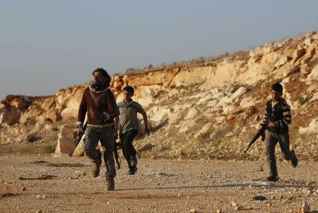 Rebel fighters carry their weapons as they run on the frontline during clashes against forces of Syria's President Bashar al-Assad in the Handarat area, north of Aleppo November 11, 2014. REUTERS/Hosam Katan