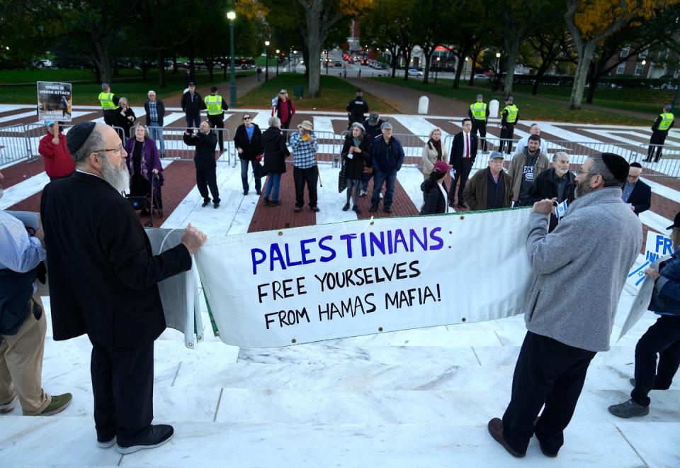 Jeffrey Gladstone and Russell Raskin hold up a banner on the steps of the State House during a pro-Israel rally Tuesday evening.