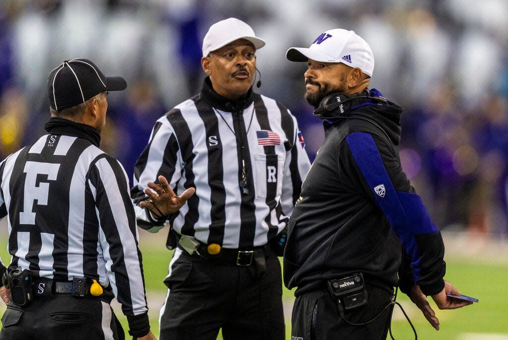 Washington head coach Jimmy Lake, right, reacts while talking with field judge Jeffrey Yock, left, and referee Michael Mothershed, center, during the first half against Oregon. The Dawgs lost, Lake came under fire for treatment of a player, and fired offensive coordinator John Donovan on Sunday.