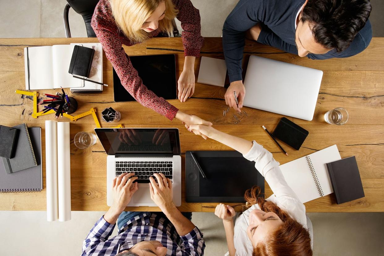 business meeting group at a table shaking hands