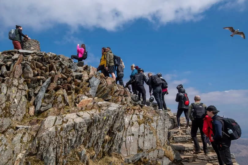 Members of the public queue to reach the trig point at the summit of Mount Snowdon on April 17, 2021