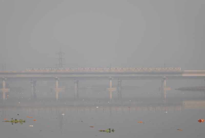 FILE PHOTO: A metro train moves over a bridge built over the Yamuna river on a smoggy morning in the old quarters of Delhi