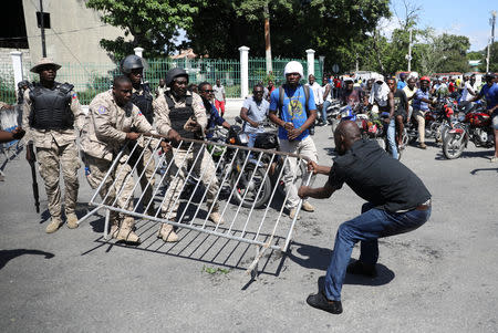 A protester grabs a fence from Haitian National Police officers during a march to demand an investigation into what they say is the alleged misuse of Venezuela-sponsored PetroCaribe funds, in Port-au-Prince, Haiti, October 17, 2018. REUTERS/Andres Martinez Casares