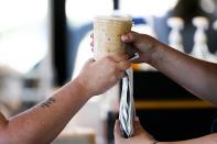 Customers pick up their drinks at a Starbucks retail location, Wednesday, June 28, 2023, in Seattle. Part of the company's goals is to cut waste, water use and carbon emissions in half by 2030. (AP Photo/Lindsey Wasson)