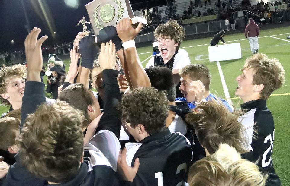 The Stowe Raiders celebrate with the trophy after their 3-0 win over Peoples Academy in the D3 State Championship game on Friday night at South Burlington's Munson Field.
