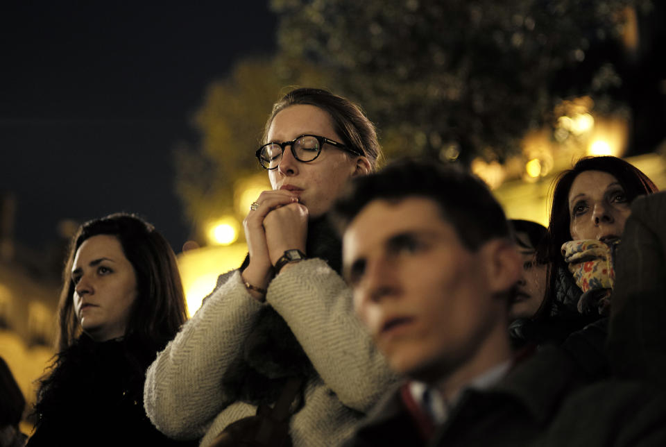 People attend a vigil in Paris, Tuesday April 16, 2019. Firefighters declared success Tuesday in a more than 12-hour battle to extinguish an inferno engulfing Paris' iconic Notre Dame cathedral that claimed its spire and roof, but spared its bell towers and the purported Crown of Christ. (AP Photo/Kamil Zihnioglu)