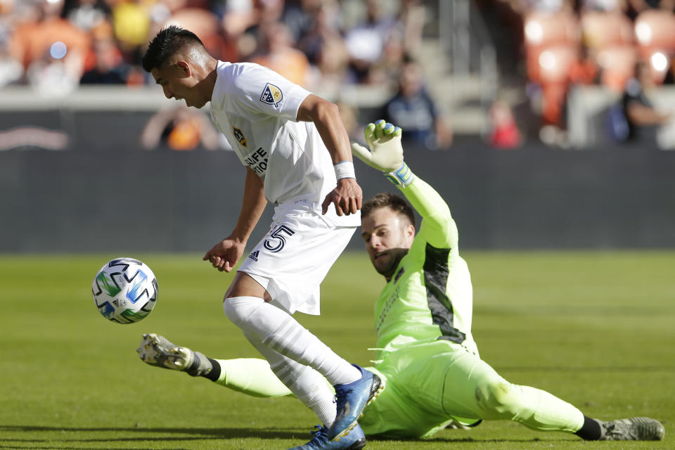 Los Angeles Galaxy midfielder Joe Corona (15) attempts a shot on goal past Houston Dynamo goalkeeper Marko Maric (1) during the second half of an MLS soccer match Saturday, Feb. 29, 2020, in Houston. (AP Photo/Michael Wyke)