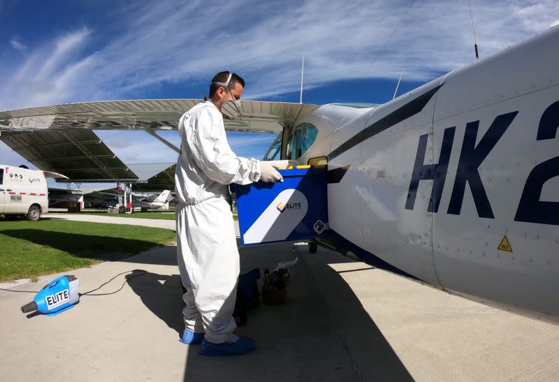 A man wearing protective gear disinfects a plane before takeoff of a flight that goes to villages with difficult access to collect samples of coronavirus disease (COVID-19), in Bogota