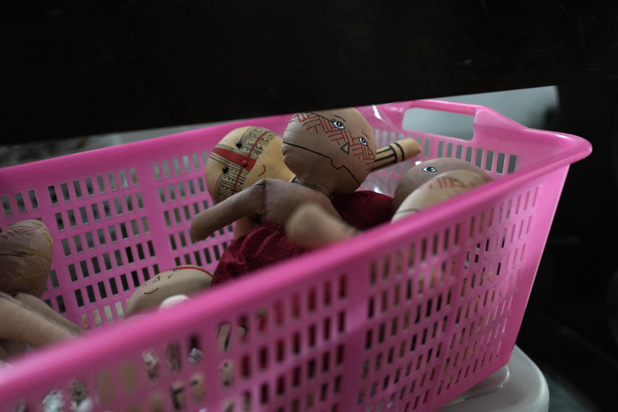 Unfinished dolls bearing faces and body paints of different Indigenous groups sit in a basket in Luakam Anambe's sewing workshop in Rio de Janeiro, Brazil, Tuesday, May 24, 2022. Each one of them is hand sown, dressed in clothes created by Luakam Anambe, of Brazil’s Anambe Indigenous group, and carefully painted by her daughter Atyna Pora. (AP Photo/Silvia Izquierdo)