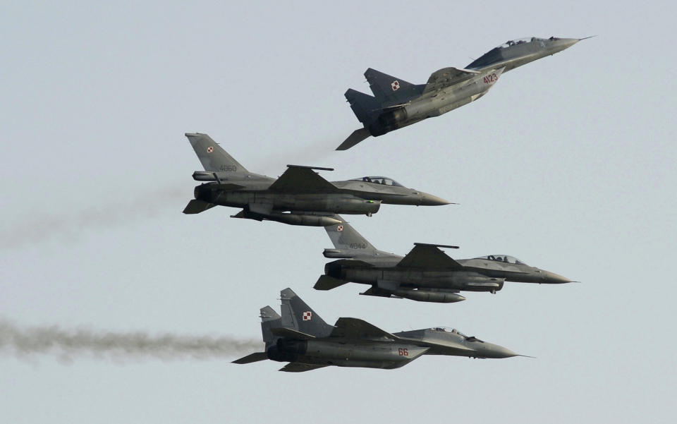 Two Polish Air Force Russian made MiG-29s fly above and below two Polish Air Force U.S. made F-16 fighter jets.
