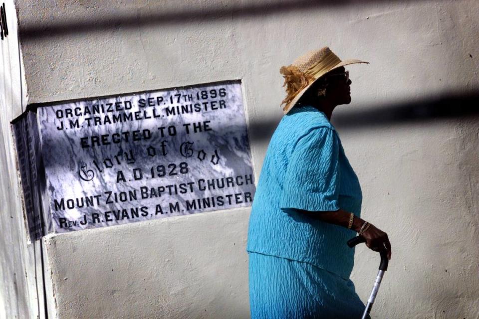 Dorothy Lowrie walks past a sign on the exterior of the Historic Mount Zion Missionary Baptist Church in Miami’s Overtown.