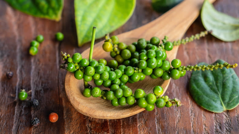 Fresh green peppercorns on wooden spoon