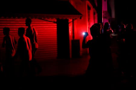 People walk on the street during a blackout in Caracas