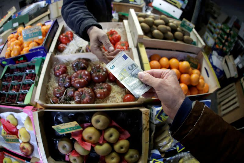 FILE PHOTO: A shopper pays with a Euro bank note in a market in Nice