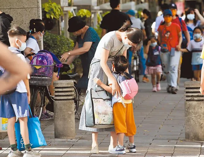 台北市疫情趨緩，高中以下學校6日正式恢復實體上課。圖為一位學童不願進校門，家長停下腳步安撫小孩。（陳俊吉攝）