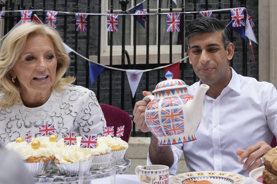 LONDON, ENGLAND - MAY 07: Britain's Prime Minister Rishi Sunak holds an oversized tea pot as he goes to pour a cup while sitting next to US First Lady Jill Biden as they attend the Big Lunch party on May 7, 2023 in London, England. Dignitaries and guests will include the First Lady of the United States of America, Dr. Jill Biden. (Photo by Frank Augstein - WPA Pool/Getty Images)