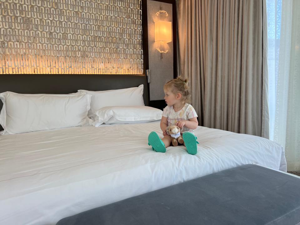 A toddler sitting on top of a hotel bed.