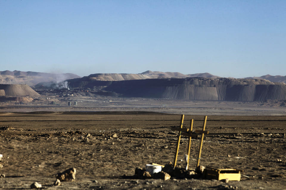 In this Sept. 28, 2012 photo, three crosses stand off the side of a highway where people died in a car accident near the Chuquicamata copper mine, behind, in the Atacama desert in northern Chile. Experts say that by 2019 the Chuquicamata copper mine will be unprofitable, so state-owned mining company Codelco is trying to head off closure by converting the open pit into the world's largest underground mine. Codelco believes the mine still has much more to give, with reserves equal to about 60 percent of all the copper exploited in the mine's history still buried deep beneath the crater. (AP Photo/Jorge Saenz)