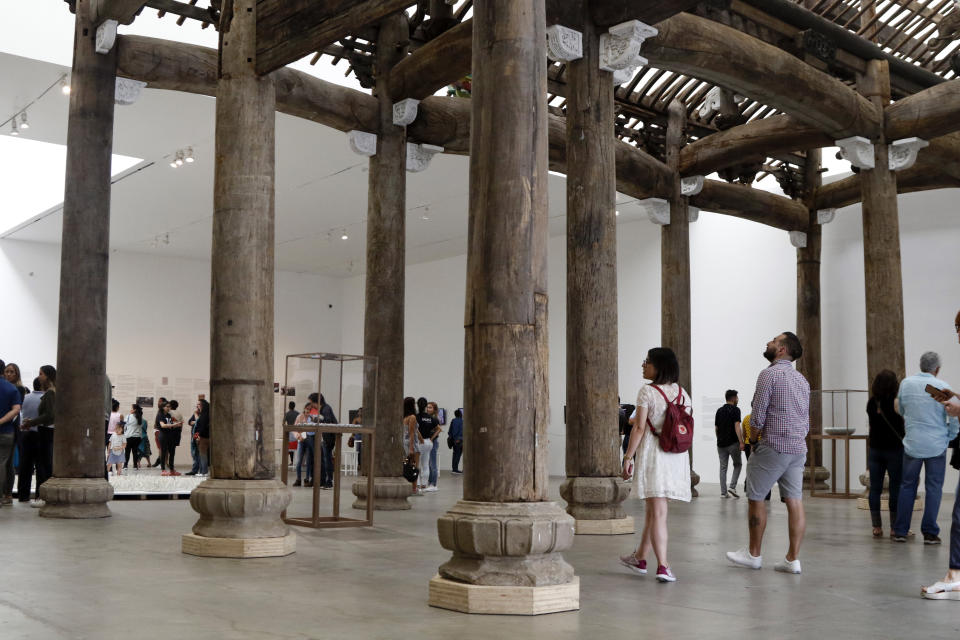 People walk through a piece titled "Ancestral Hall of the Wang Family," part of an ancient Chinese construction rescued by Chinese concept artist and government critic Ai Weiwei, at the Contemporary Art University Museum (MUAC ) in Mexico City, Mexico, Saturday, April 13, 2019. The piece creates a striking contrast between the remote memory of his country and the recent memory of Mexico, at the exhibit titled "Reestablish Memories." (AP Photo/Claudio Cruz)