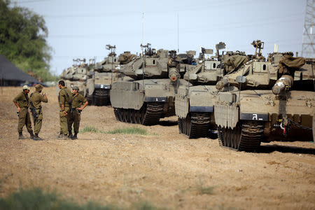 Israeli soldiers speak next to tanks as military armoured vehicles gather in an open area near Israel's border with the Gaza Strip October 18, 2018. REUTERS/Amir Cohen