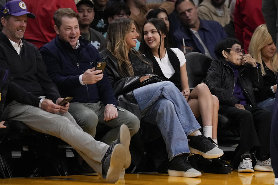 Tate McRae, center left, and Olivia Rodrigo, center right, watch the first half of an NBA basketball game between the Brooklyn Nets and the Los Angeles Lakers in Los Angeles, Friday, Jan. 19, 2024. (AP Photo/Ashley Landis)
