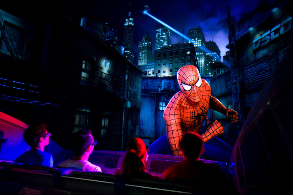A group of riders watch Spider-Man on screen at "The Amazing Adventures of Spider-Man"