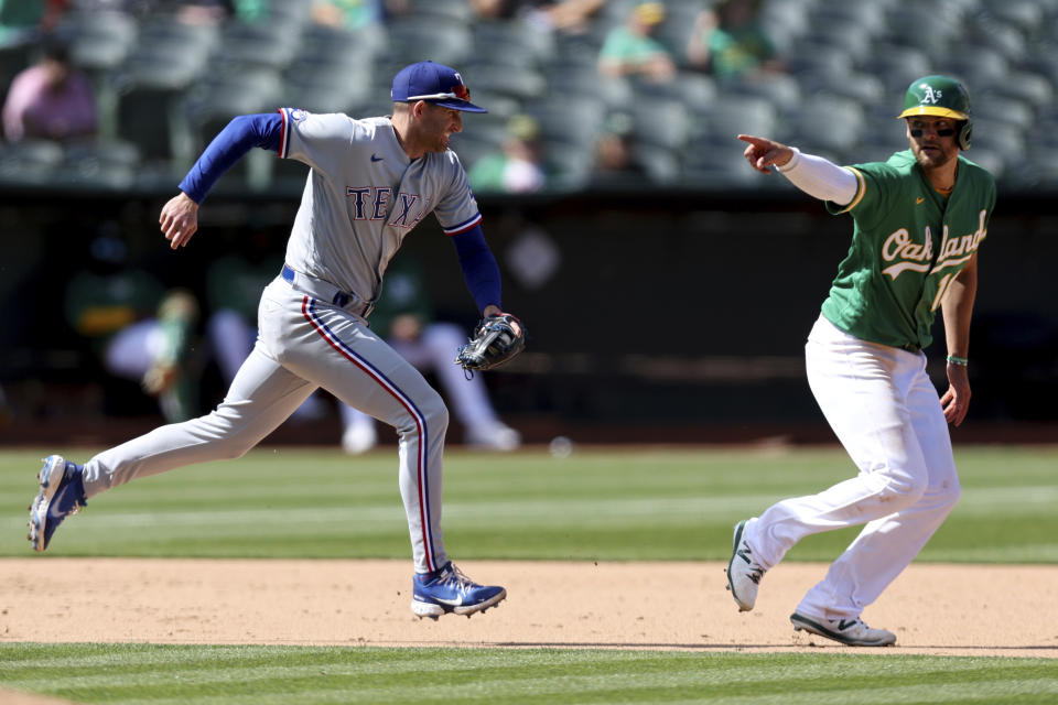 Texas Rangers' Brad Miller, left, runs to tag out Oakland Athletics' Chad Pinder on a ball hit by Elvis Andrus, who was safe during the seventh inning of a baseball game in Oakland, Calif., Saturday, May 28, 2022. (AP Photo/Jed Jacobsohn)