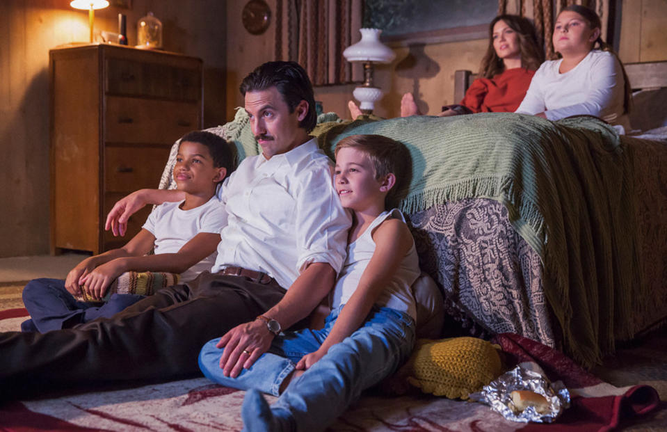 Lonnie Chavis, Milo Ventimiglia, Parker Bates, Mackenzie Hancsicsak, Mandy Moore are sitting on a bed and floor, watching something together in a cozy room