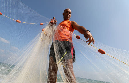 Palestinian fisherman Jihad al-Soltan prepares his fishing net on a beach in the northern Gaza Strip August 21, 2017. REUTERS/Mohammed Salem