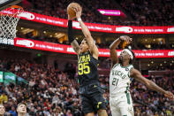 Utah Jazz forward Juan Toscano-Anderson (95) goes for dunk past the defensive swing of Milwaukee Bucks guard Jrue Holiday (21) during the first half of an NBA basketball game Friday, March 24, 2023, in Salt Lake City. (AP Photo/Adam Fondren)