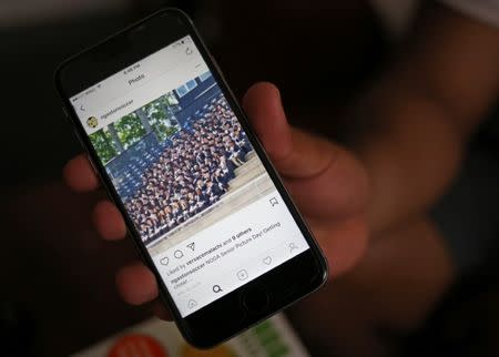 Raul Contreras, 19, of Honduras, who is seeking refugee status in Canada, shows a photo of his North Carolina high school graduation class while at a long-stay hotel in Toronto, Ontario, Canada April 9, 2017. Picture taken April 9, 2017. REUTERS/Chris Helgren