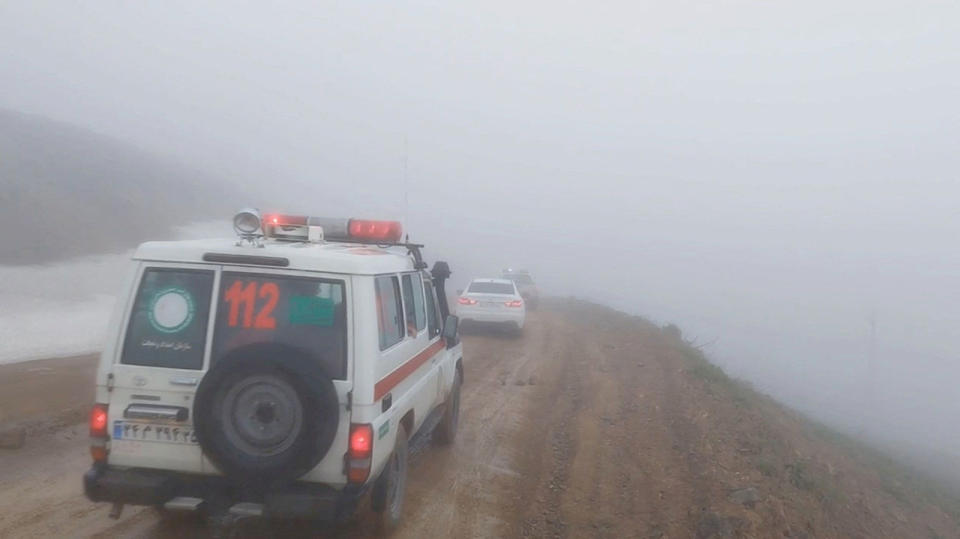 En esta imagen de un vídeo, una ambulancia y otros vehículos circulan por una carretera con niebla tras el accidente de un helicóptero que transportaba al presidente de Irán, Ebrahim Raisi, en Varzaqan, provincia de Azerbaiyán Oriental, Irán, el 19 de mayo. (Crédito: Sociedad de la Media Luna Roja Iraní/Handout/Reuters)