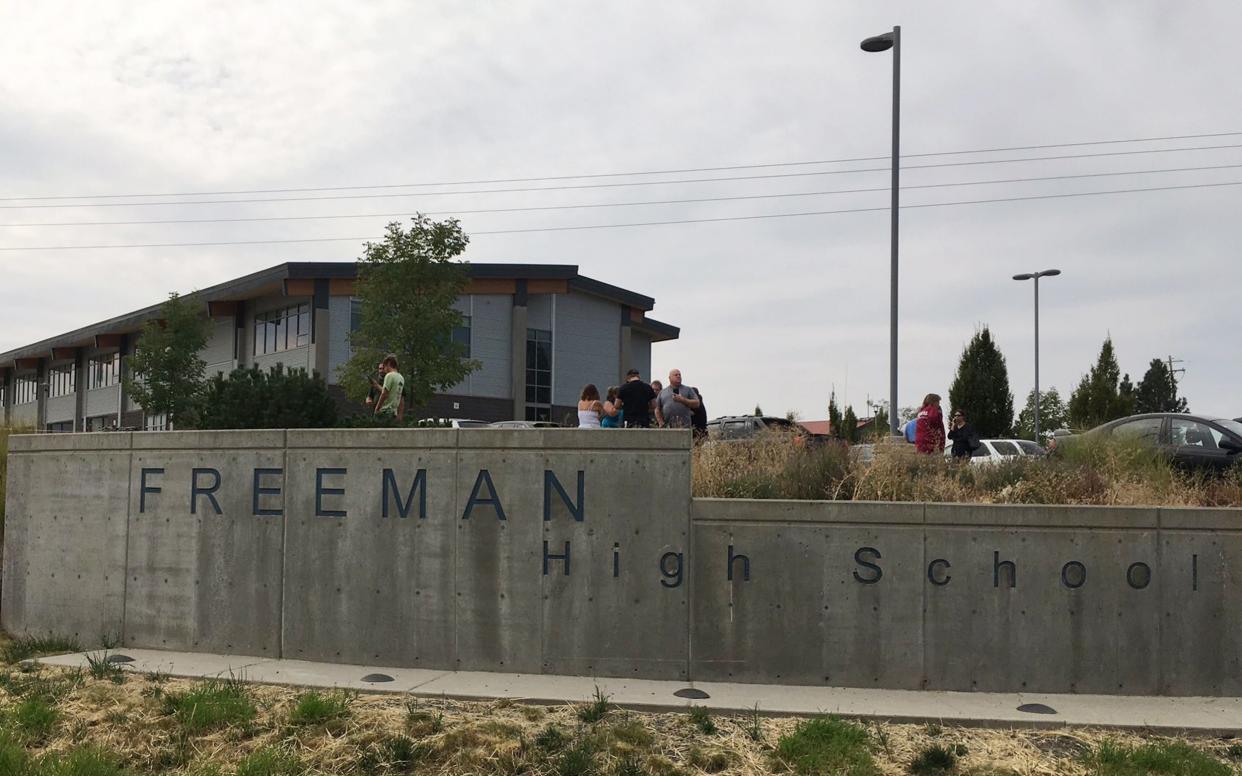 Parents gather at Freeman High School where a suspect has been arrested after shooting a student dead - KHQ via AP