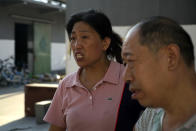 Yu Ruiping, left, and her husband Lu Jinlin, right, stand outside a family warehouse in Xinxiang in central China's Henan Province, Monday, July 26, 2021. Record rain in Xinxiang last week left the couple's goods in a nearby market underwater, causing losses that could run into the tens of thousands of dollars. Dozens of people died in the floods that immersed large swaths of central China's Henan province in water. (AP Photo/Dake Kang)