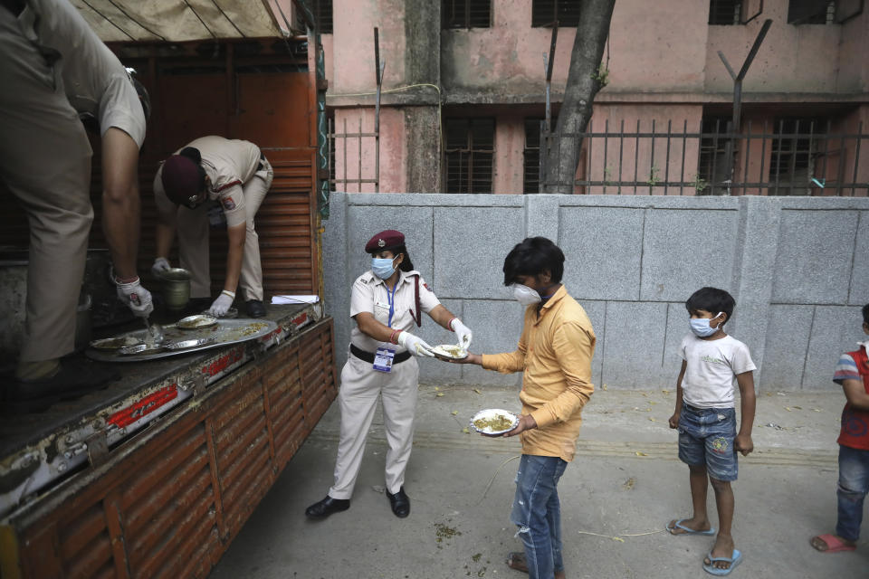 Delhi policewomen distribute food prepared by the Bangla Sahib Gurdwara kitchen in an impoverished locality in New Delhi, India, Sunday, May 10, 2020. The Bangla Sahib Gurdwara has remained open through wars and plagues, serving thousands of people simple vegetarian food. During India's ongoing coronavirus lockdown about four dozen men have kept the temple's kitchen open, cooking up to 100,000 meals a day that the New Delhi government distributes at shelters and drop-off points throughout the city. (AP Photo/Manish Swarup)