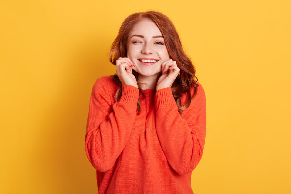 A smiling woman pinching her cheeks