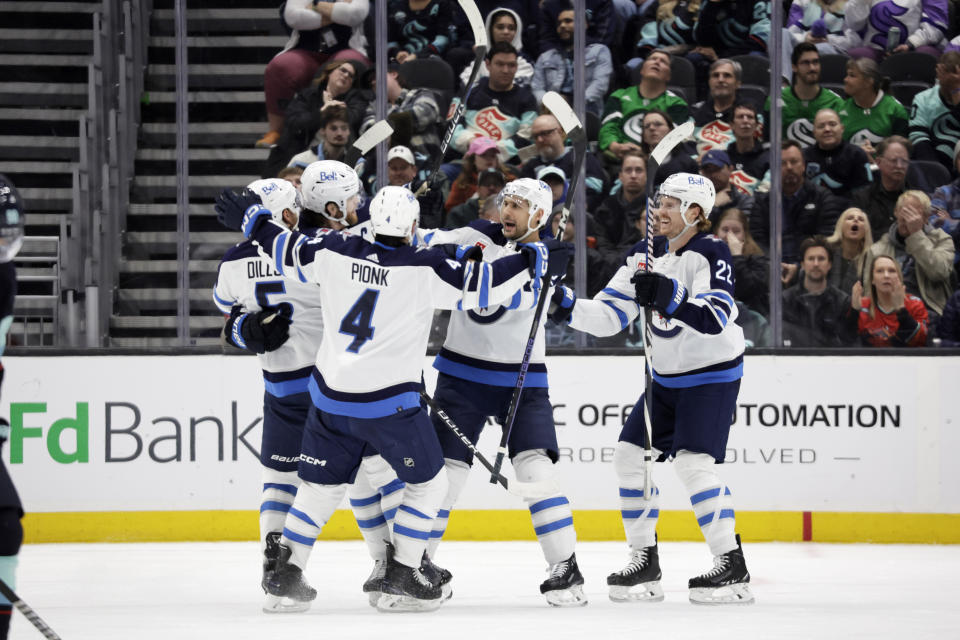 Winnipeg Jets center Adam Lowry, second from left, is surrounded by defenseman Brenden Dillon (5), defenseman Neal Pionk (4), right wing Nino Niederreiter, second from right, and center Mason Appleton (22) after scoring against the Seattle Kraken during the third period of an NHL hockey game, Friday, March 8, 2024, in Seattle. The Jets won 3-0. (AP Photo/John Froschauer)