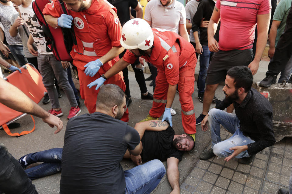 Lebanese Red Cross volunteers help an injured of Hezbollah supporters during clash with Lebanese riot policemen during a protest in Beirut, Lebanon, Friday, Oct. 25, 2019. Leader of Lebanon's Hezbollah calls on his supporters to leave the protests to avoid friction and seek dialogue instead. (AP Photo/Hassan Ammar)