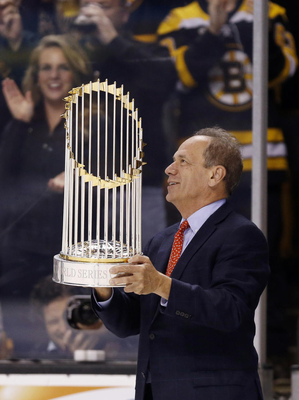 FILE - President and CEO of the Boston Red Sox Larry Lucchino holds the World Series trophy on the ice during a break in play in the second period of an NHL hockey game between the Boston Bruins and the Anaheim Ducks in Boston, Thursday, Oct. 31, 2013. Larry Lucchino, the force behind baseball’s retro ballpark revolution and the transformation of the Boston Red Sox from cursed losers to World Series champions, has died. He was 78. Lucchino had suffered from cancer. The Triple-A Worcester Red Sox, his last project in a career that also included three major league baseball franchises and one in the NFL, confirmed his death on Tuesday, April 2, 2024.(AP Photo/Michael Dwyer, File)