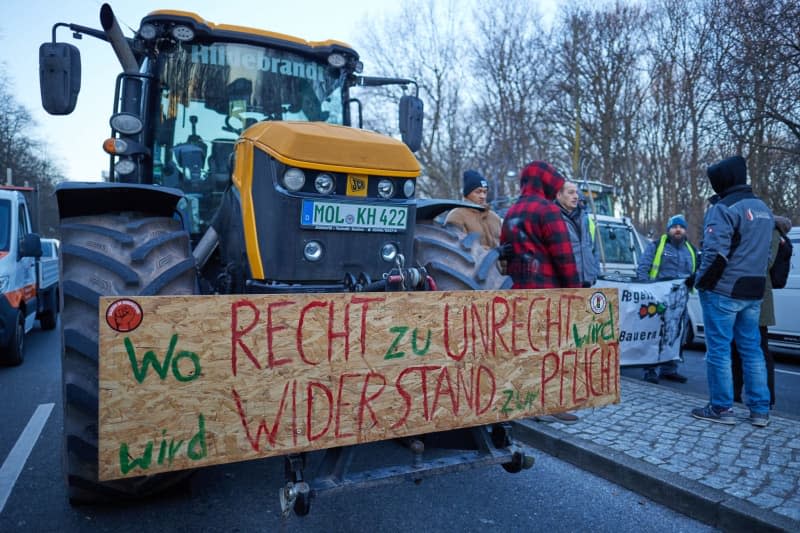 A banner reading "Where right becomes wrong, resistance becomes duty" can be seen during farmers' protest in front of the Brandenburg Gate. In response to the federal government's austerity plans, the farmers' association has called for a week of action with rallies and rallies starting on January 8. It is to culminate in a major demonstration in the capital on January 15. Jörg Carstensen/dpa