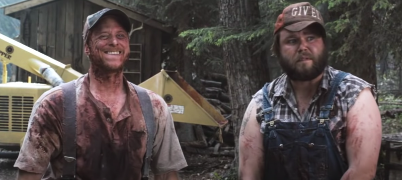 Two men stand bloodied talking to an officer