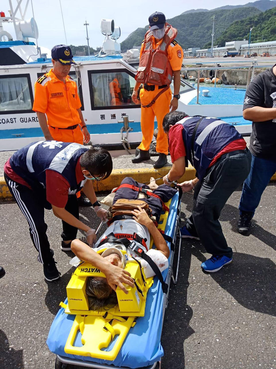 An injured people lies on stretcher at the site of a collapsed bridge in Nanfangao, eastern Taiwan. Tuesday, Oct. 1, 2019. A towering bridge over a bay in eastern Taiwan has collapsed sending an oil tanker truck falling onto boats in the water below. A disaster relief official said the collapse set off a fire and at least 10 people have been hurt. (Taiwan's Coast Guard via AP)