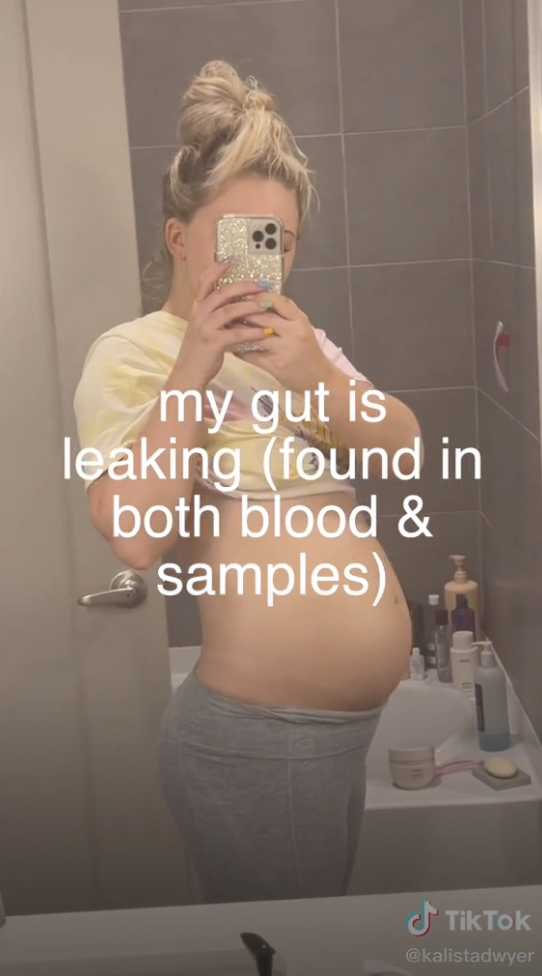 A mirror selfie of Kalista with the caption "my gut is leaking (found in both blood & samples)"