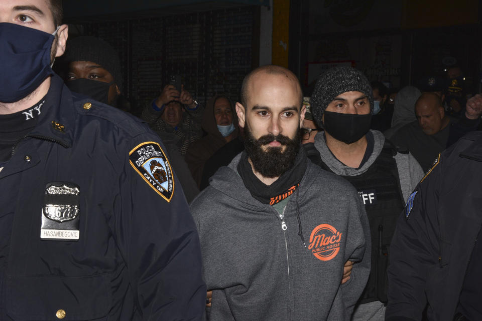 Mac's Public House co-owner Danny Presti is taken away in handcuffs after being arrested by New York City sheriff's deputies, Tuesday, Dec. 1, 2020, in the Staten Island borough of New York. Presti, who authorities said has been defying coronavirus restrictions, was taken into custody early Sunday, Dec. 6, 2020 after running over a deputy with a car, authorities said. Presti tried to drive away from his bar, Mac's Public House, as deputies were arresting him for serving patrons in violation of city and state closure orders, Sheriff Joseph Fucito said. (Steve White via AP)