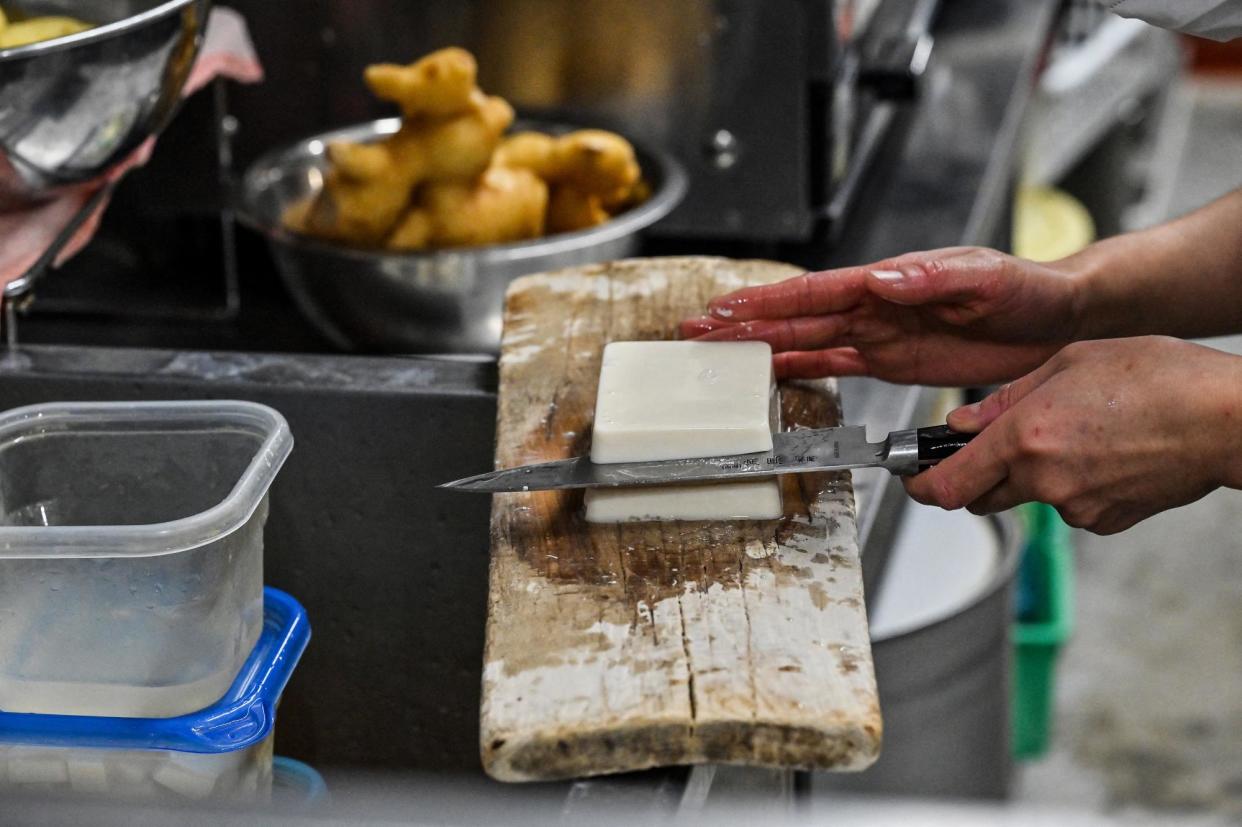 <span>A worker slices tofu at a restaurant in Tokyo, Japan, on 7 December 2023.</span><span>Photograph: Richard A Brooks/AFP via Getty Images</span>